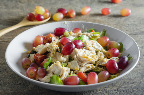mix,salad,with,grapes,and,chicken,on,white,dish